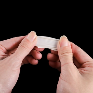 Macro shot of high elasticity white latex finger cots being stretched against black background