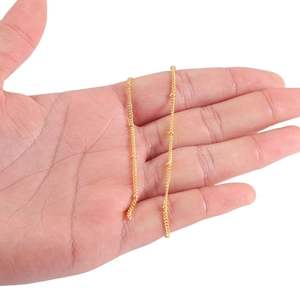 Handheld view of slim golden satellite chain with small metal beads for jewelry making