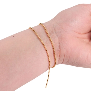 Detail of bright gold beaded copper chain worn on wrist for DIY jewelry projects