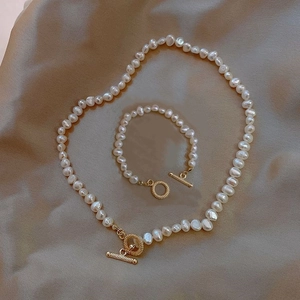 Barockperlen-Schmuckset mit goldenen OT-Verschlüssen auf elegantem Champagner-Satin