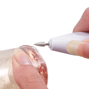 Close-up of portable nail drill using a conical metal bit for fine DIY accessory polishing
