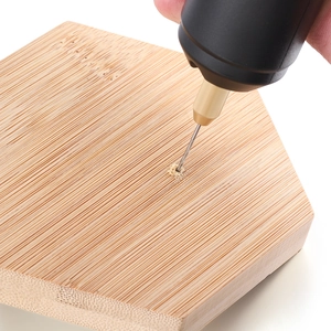 Mini USB handheld power drill with gold chuck drilling into a hexagonal bamboo wood block