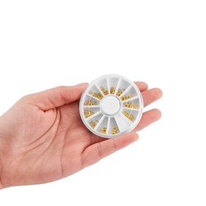 Macro shot of assorted golden alloy nail art charms in a white plastic rotating organizer