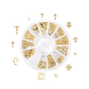 Golden metal nail art charms set with cross and iris icons in a rotating storage box