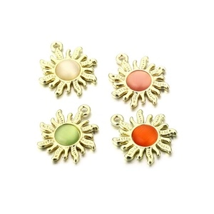 Quatre pendentifs soleil dorés avec pierres oeil de chat colorées sur fond blanc