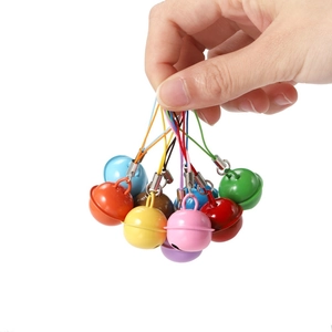 Hand holding colorful metal craft bells in red yellow blue green for DIY pet collars