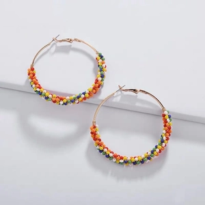Détail des perles de rocaille colorées sur boucles d'oreilles créoles dorées bohèmes