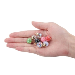 Mini glass ball pendants with colorful sequins held in hand for DIY jewelry making