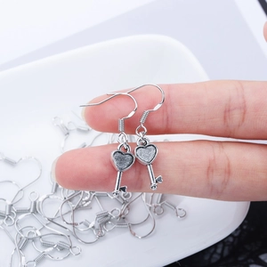 Detail of silver heart-shaped key pendant earrings with vintage industrial matte finish