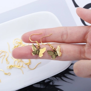 Detail of golden butterfly earring hooks with textured surface on a white ceramic plate