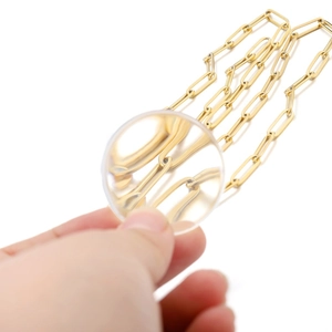 Detailed view of golden stainless steel rolo chain under a magnifying glass for DIY jewelry