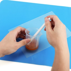 Resin mixing tools set with measuring cup and white stirrer on silicone mat