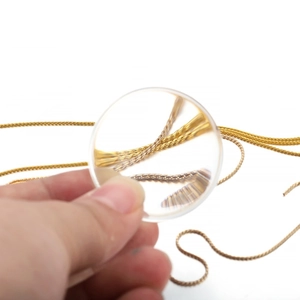 Macro view of gold and silver plated jewelry chains under a magnifying glass