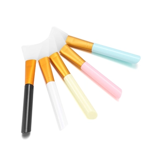 Five colorful silicone facial mask brushes with gold ferrules in a fan arrangement