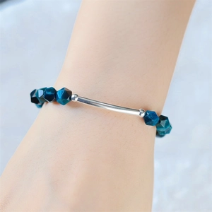 Detail eines geflochtenen Armbands mit facettierten blauen Steinen und glatter Silberröhre