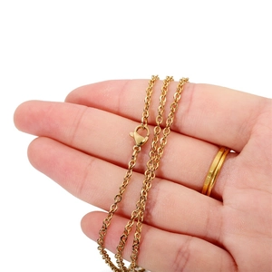 Detail of golden stainless steel chain with lobster clasp held in hand on white background