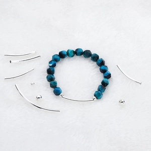 Detail von facettierten blauen Tigerauge-Perlen und poliertem Silberrohr für DIY-Armband