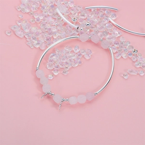 Geflochtenes Armband mit Silberrohren, rosa Mattsteinen und Blitzanhängern auf rosa Basis