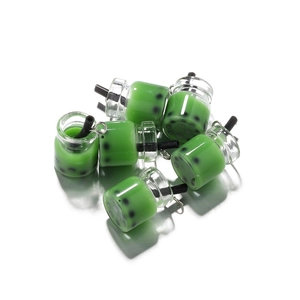 Dettaglio di mini ciondoli al tè matcha con perle nere e anelli di metallo argentato