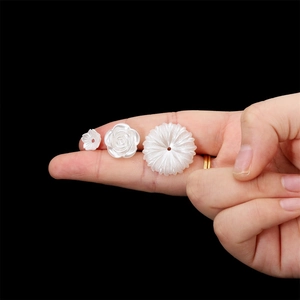 Dettaglio macro di ciondoli a fiore e rose perlate bianche per gioielli fai-da-te