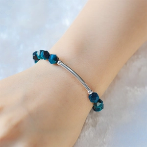 Bracciale a tubo curvo in argento lucido con gemme sfaccettate blu scuro al polso