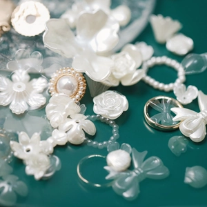 Vista macro di ciondoli a fiore e fiocco in perla bianca per creazione di gioielli DIY