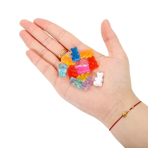 Close-up of colorful resin gummy bears on hand showing size for DIY jewelry making