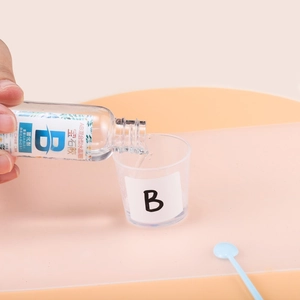 Gieten van component B verharder voor 3:1 epoxyhars sieradenset in een maatbeker