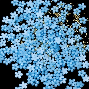 Macro shot of light blue resin five-petal nail flowers with tiny golden metal beads