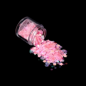 Macro shot of assorted pink fairy glitter and sequins spilled from a clear jar