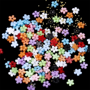 Macro shot of colorful resin five-petal flowers with gold steel beads for nail art