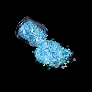 Macro shot of laser blue holographic nail art sequins and glitter mix in a clear jar