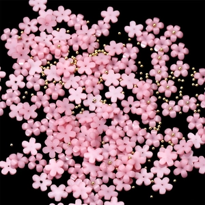 Macro shot of 3D pink resin flower nail charms with golden bead centers for DIY art