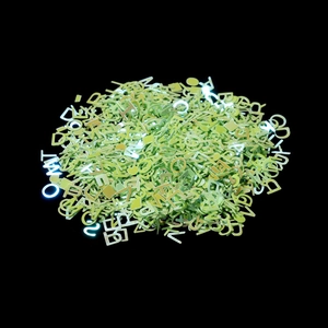Macro shot of green metallic alphabet charms for DIY jewelry and nail art crafts