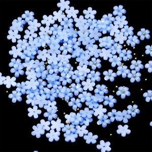 Macro shot of light blue resin flowers and gold beads for DIY nail art decoration
