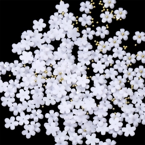 Macro detail of white resin 3D flowers with gold metal beads for nail art design