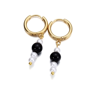 Close-up of gold hoop earrings with contrasting black and white pearl beaded charms