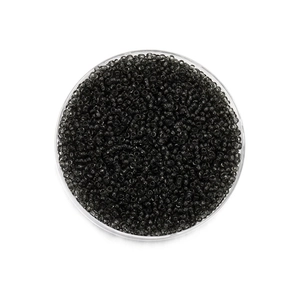 Vue macro de perles de rocaille en verre gris foncé de 2mm dans un contenant rond