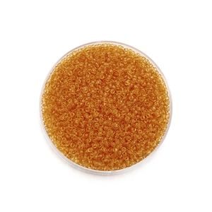 Détails macro de perles de rocaille ambre transparent pour bijoux DIY en plateau rond