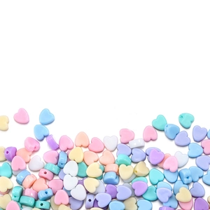 Dettaglio di perline a forma di cuore in acrilico colorato con fori per creazione gioielli DIY
