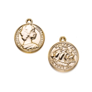 Macro detail of gold-plated alloy pendants with relief of Queen Elizabeth II and sailboat