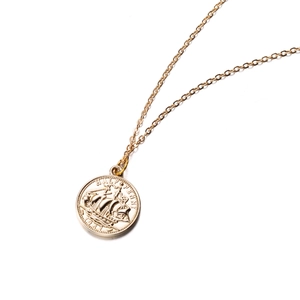 Macro shot of gold half penny coin pendant with ship engraving and vintage finish details
