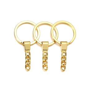 Detail van drie glanzende gouden metalen sleutelhangers met platte ringen en kettingen