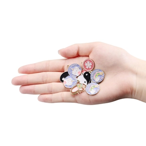 Assorted colorful enamel fruit and paw charms held in hand for DIY jewelry making