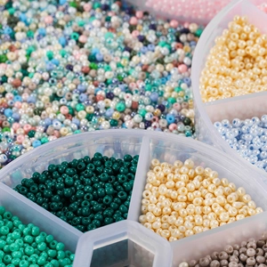 Detaillierte Makroansicht bunter 2mm Glasperlen in einer klaren Kunststoff-Box