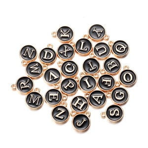 Detail view of 26 alphabet charms with gold metal finish and black enamel for DIY jewelry