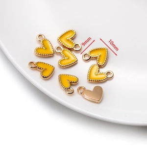 Détail de 7 pendentifs cœurs en émail jaune avec bords dorés mesurant 9mm par 10mm