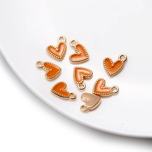 Détail macro de pendentifs cœur en émail orange avec bord perlé doré pour bijoux