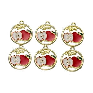 Detail of red and white enamel apple charms with gold metal frames and hanging loops