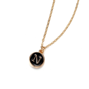 Elegant gold letter N necklace with round black enamel pendant on a white background